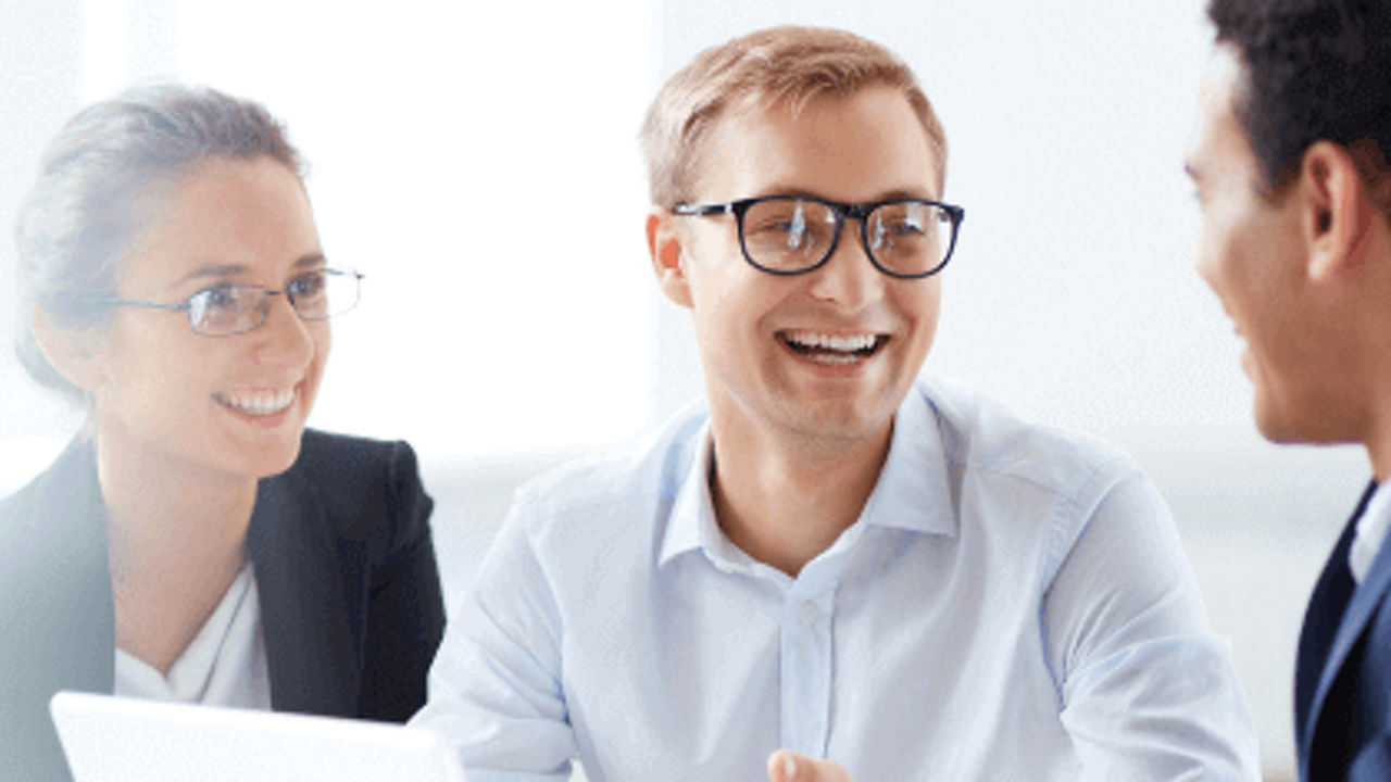 2 businessmen and 1 businesswoman smiling at each other and talking 