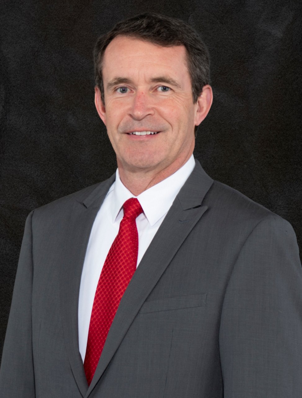 Mike Field headshot in grey suit with a red tie