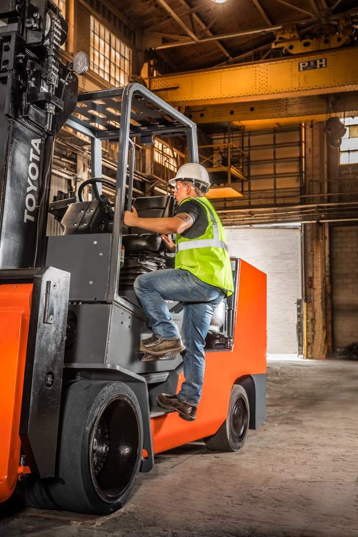 Man safely entering Toyota forklift in warehouse