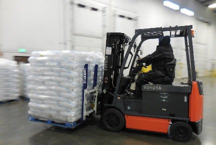 A Toyota forklift carrying a pallet with many ice bags in a warehouse