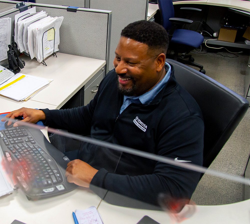 Male tmh office associate smiling at desk 