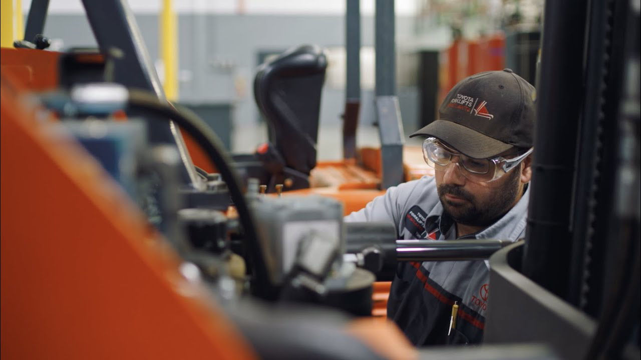 Male technician working on Toyota forklift in warehouse